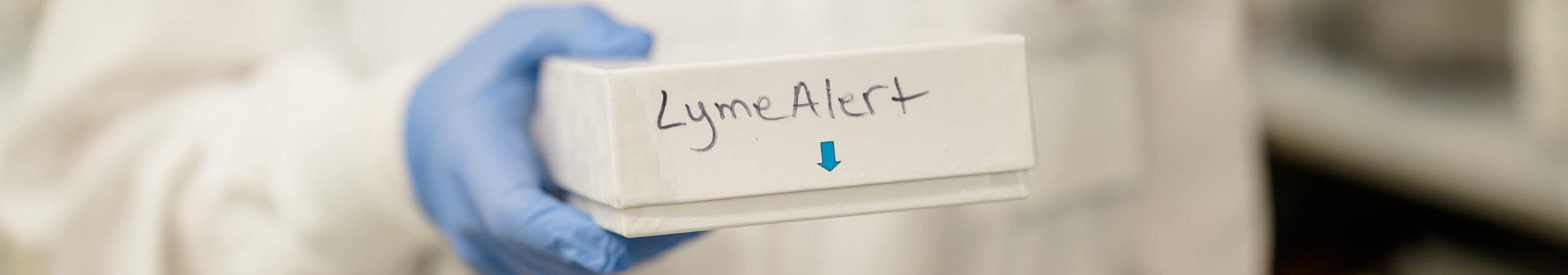 Medical professional holding a Lyme disease test kit in a lab setting.