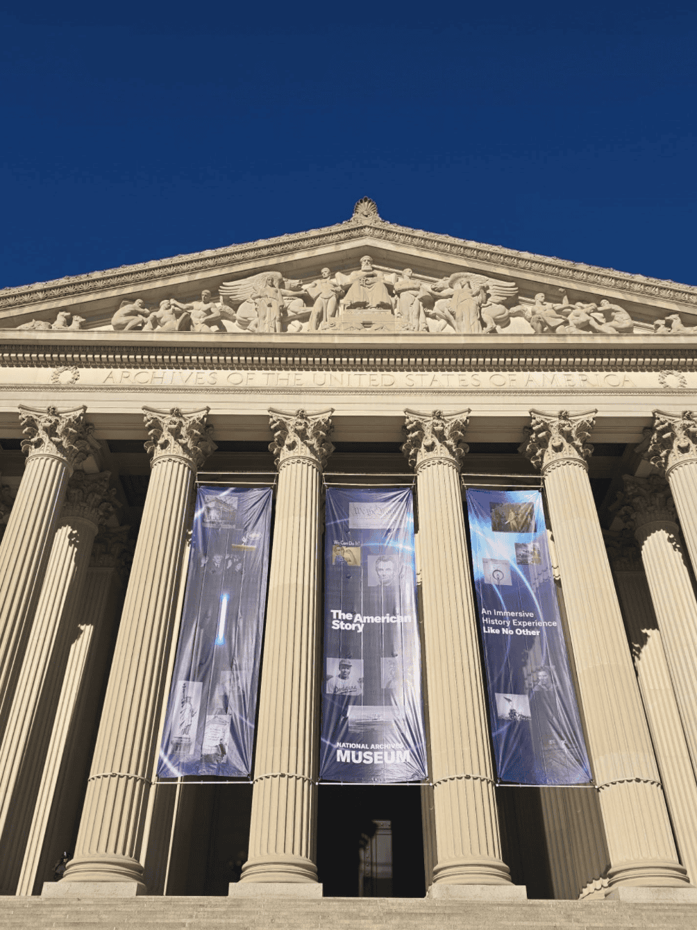 25 Ancient Greek-style museum facade featuring tall, ornate columns and large banners hanging between t.
